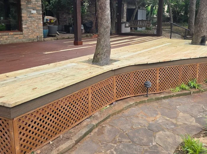 Finished curved deck around backyard trees, stained red with lattice skirting