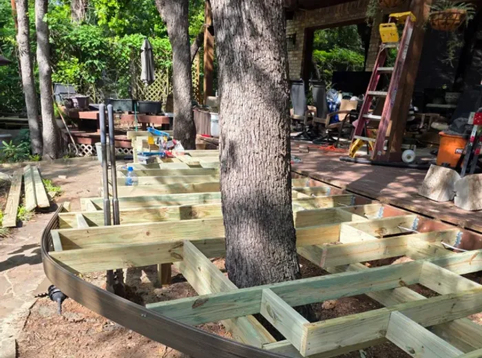 Deck framing under construction around backyard trees